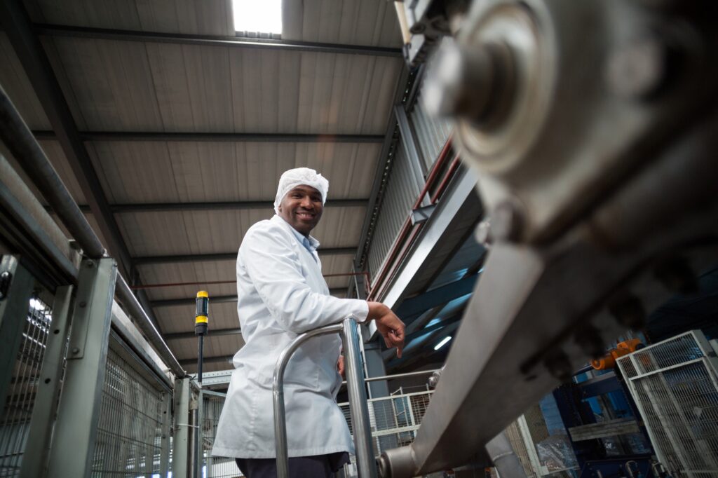 Smiling factory engineer standing in bottle factory